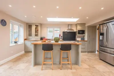 a kitchen with a large island with two bar stools at Buoys Cottage, Orford in Orford