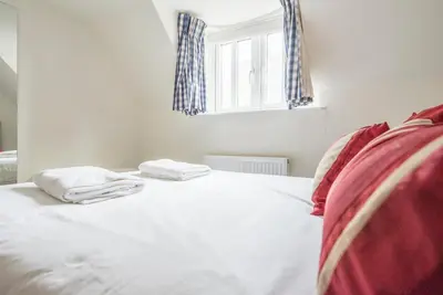 a bedroom with a white bed with two towels on it at Buoys Cottage, Orford in Orford