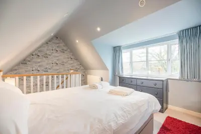 a bedroom with a large white bed and a window at Buoys Cottage, Orford in Orford
