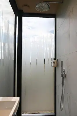 a glass shower door in a bathroom with a sink at Mirror Houses Pound Farm - Meadow OOD in Saxmundham