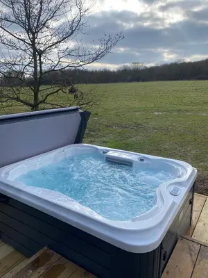a hot tub on a deck with a field in the background at Mirror Houses Pound Farm - Pond OOD in Saxmundham