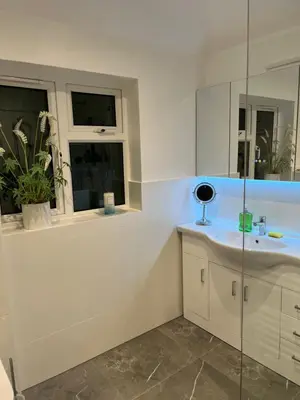 a white bathroom with a sink and two windows at House in city centre with free parking in Cambridge