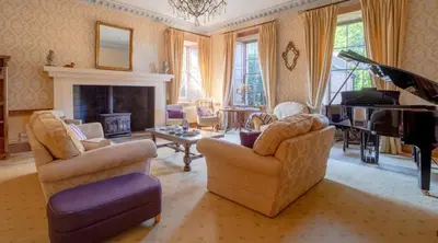a living room with two chairs and a piano at Hockwold Hall - Former Royal residence in Hockwold cum Wilton