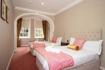 two beds in a bedroom with pink and white at Hockwold Hall - Former Royal residence in Hockwold cum Wilton