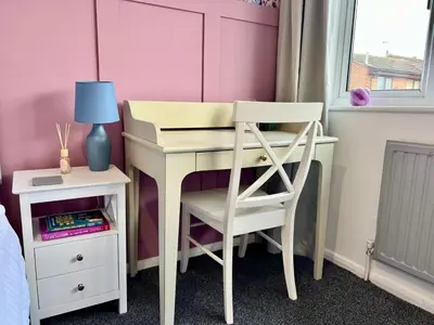 a desk with a chair and a table with a lamp at Bright, artsy 3BR home with parking & long term stay in Saffron Walden
