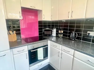 a kitchen with white cabinets and a pink at Bright, artsy 3BR home with parking & long term stay in Saffron Walden