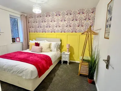 a bedroom with a bed with a red blanket at Bright, artsy 3BR home with parking & long term stay in Saffron Walden