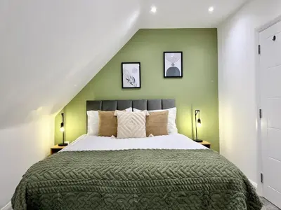 a bedroom with a large bed with green walls at Bright, artsy 3BR home with parking & long term stay in Saffron Walden