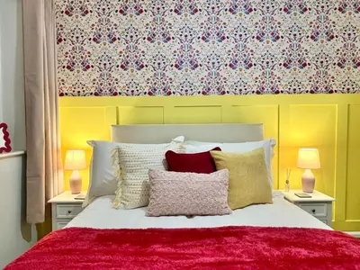 a bedroom with a bed with a red blanket and pillows at Bright, artsy 3BR home with parking & long term stay in Saffron Walden