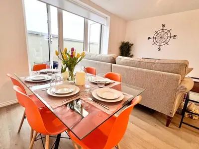 a dining room with a table and chairs and a couch at Bright, artsy 3BR home with parking & long term stay in Saffron Walden