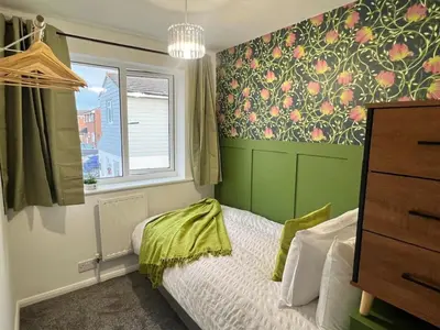 a bedroom with a bed with a green wall at Bright, artsy 3BR home with parking & long term stay in Saffron Walden