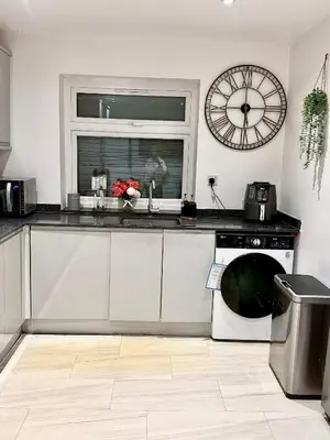 a kitchen with a dishwasher and a clock on the wall at Deluxe Spacious King Size Room in Hornchurch