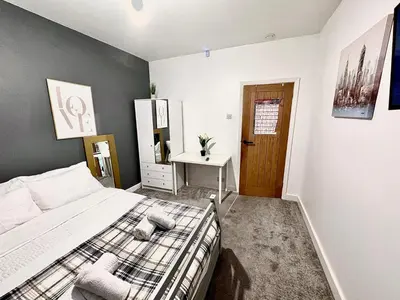 a bedroom with a bed and a desk in it at Double bedrooms In Spacious Home in Harold Wood