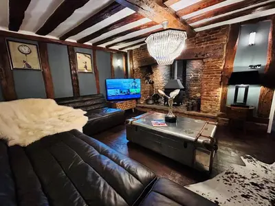 a living room with a leather couch and a tv at The Foremans House, With Hot Tub, A luxurious Historical pre 16th Century Grade II Listed House, location Essex in a picturesque Village, Country Pub In walking Distance in Ridgewell