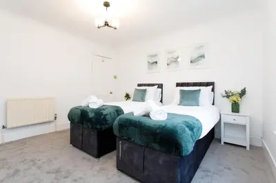 a bedroom with two beds with green cushions at Cosy House - Stanstead Airport in Bishops Stortford