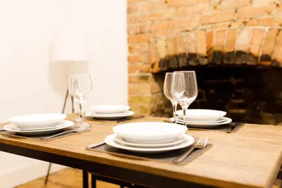 a wooden table with plates and wine glasses on it at Cosy House - Stanstead Airport in Bishops Stortford