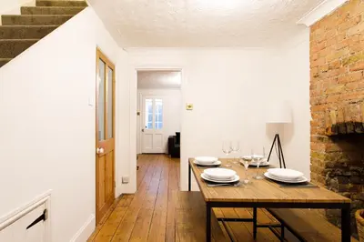 a dining room with a table and a brick wall at Cosy House - Stanstead Airport in Bishops Stortford