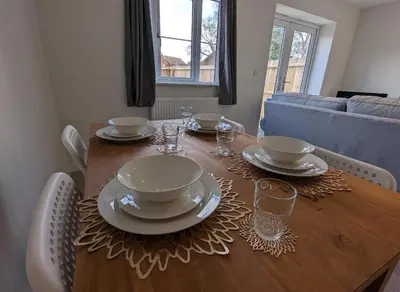 a dining room table with plates and glasses on it at Newly Built Thetford Retreat in Watton