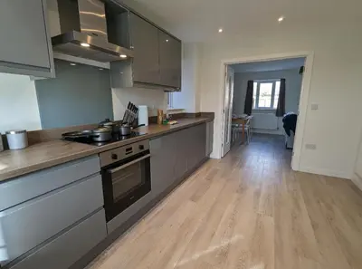 a kitchen with stainless steel appliances and a wooden floor at Newly Built Thetford Retreat in Watton