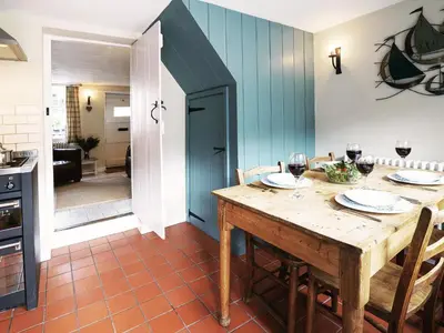 a dining room with a table with glasses of wine at 6 Town Steps by The Suffolk Cottage Collection in Aldeburgh