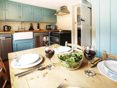 a kitchen with a table with two glasses of wine at 6 Town Steps by The Suffolk Cottage Collection in Aldeburgh