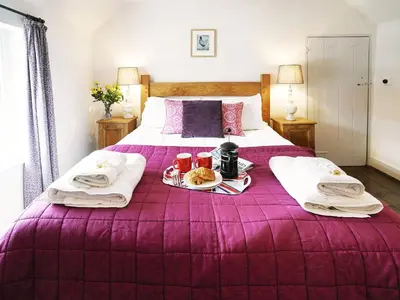 a purple bed with a tray of food on it at Tiger Villa by The Suffolk Cottage Collection in Aldeburgh