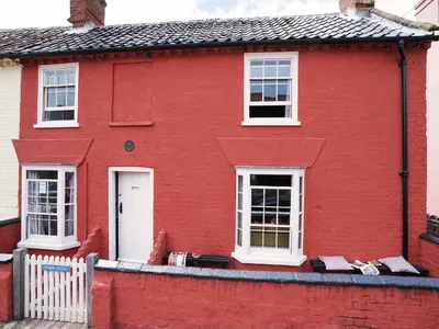 a red house with white windows and a white fence at Tiger Villa by The Suffolk Cottage Collection in Aldeburgh