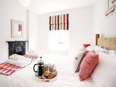 a white bed with a tray of food on it at Sandpiper Cottage by The Suffolk Cottage Collection in Aldeburgh