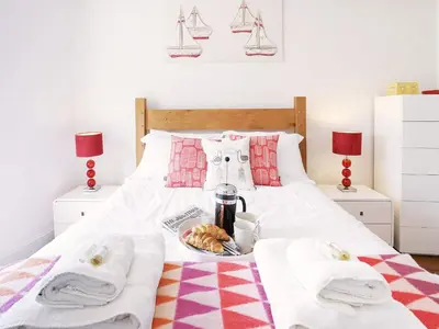 a bed with a tray of food on it at Sandpiper Cottage by The Suffolk Cottage Collection in Aldeburgh