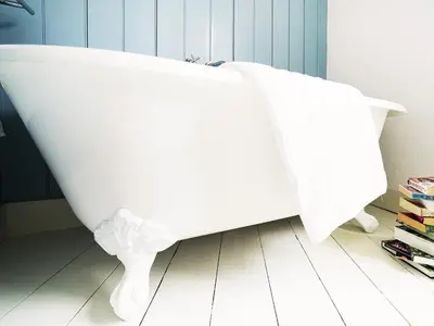 a white bath tub sitting on top of a bathroom floor at Sandpiper Cottage by The Suffolk Cottage Collection in Aldeburgh