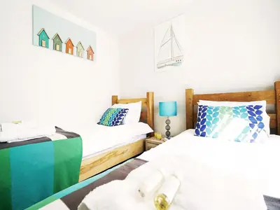 a bedroom with two beds and a sailboat on the wall at Sandpiper Cottage by The Suffolk Cottage Collection in Aldeburgh