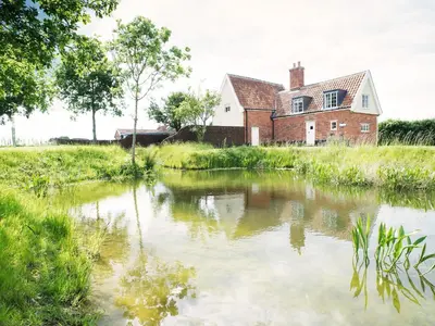 a house and a pond in front of a house at The Cottage by The Suffolk Cottage Collection in Peasenhall