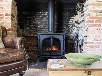 a fireplace in a living room with a bowl on a table at The Cottage by The Suffolk Cottage Collection in Peasenhall