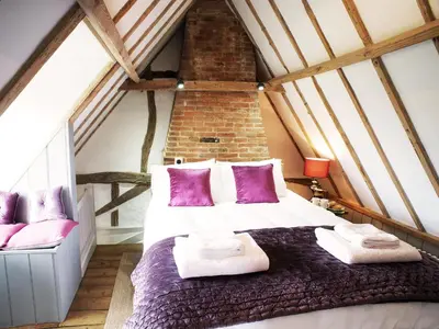 a bedroom with a large bed in a attic at The Cottage by The Suffolk Cottage Collection in Peasenhall
