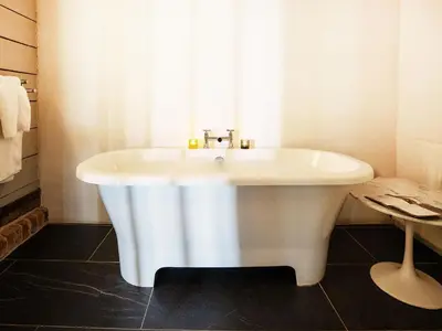 a white bath tub in a bathroom with a window at The Seed Store by The Suffolk Cottage Collection in Peasenhall