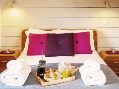 a bed with towels and a tray of food on it at The Seed Store by The Suffolk Cottage Collection in Peasenhall