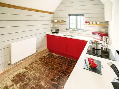 a kitchen with red cabinets and a white counter top at The Seed Store by The Suffolk Cottage Collection in Peasenhall