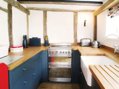 a kitchen with blue cabinets and a stove at The Cross Wing by The Suffolk Cottage Collection in Peasenhall