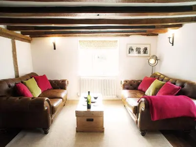 a living room with brown leather couches and a table at The Cross Wing by The Suffolk Cottage Collection in Peasenhall