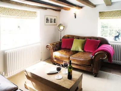 a living room with a couch and a table with wine glasses at The Cross Wing by The Suffolk Cottage Collection in Peasenhall