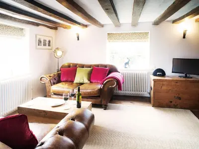a living room with a couch and a table at The Cross Wing by The Suffolk Cottage Collection in Peasenhall