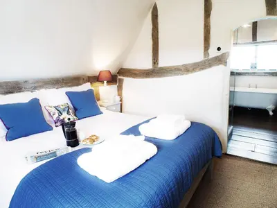 a bedroom with a bed with blue and white sheets at The Cross Wing by The Suffolk Cottage Collection in Peasenhall
