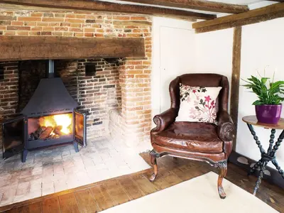 a leather chair in a living room with a fireplace at The Cross Wing by The Suffolk Cottage Collection in Peasenhall