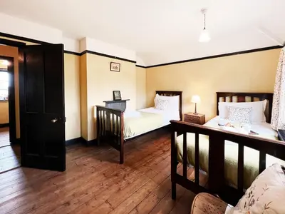 two beds in a room with wooden floors at The Vintage House by The Suffolk Cottage Collection in Aldeburgh