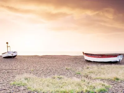 two boats sitting on the beach at sunset at The Vintage House by The Suffolk Cottage Collection in Aldeburgh