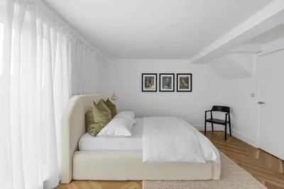 a white bedroom with a bed with white curtains at Navigation Yard in Chelmsford