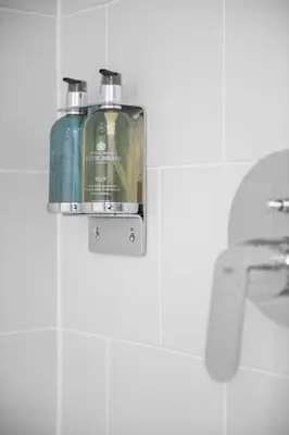 a soap dispenser hanging on a wall next to a sink at Navigation Yard in Chelmsford