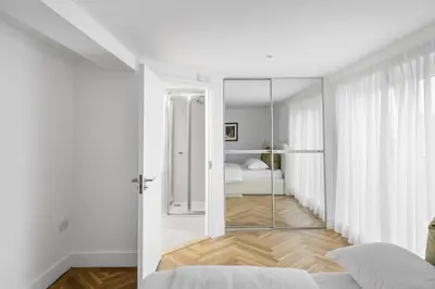 a white bedroom with a bed and a mirror at Navigation Yard in Chelmsford