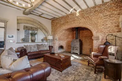 a living room with a couch and a brick fireplace at Gatehouse East in Saint Osyth