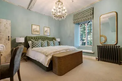 a bedroom with a large bed and a chandelier at Gatehouse East in Saint Osyth